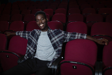 Portrait of happy man sitting in theatreの写真素材