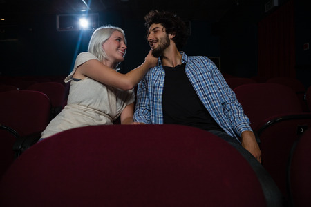Loving couple looking at each other while sitting in the theatreの写真素材