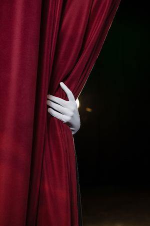 Close-up of hand in a white glove pulling curtain awayの写真素材