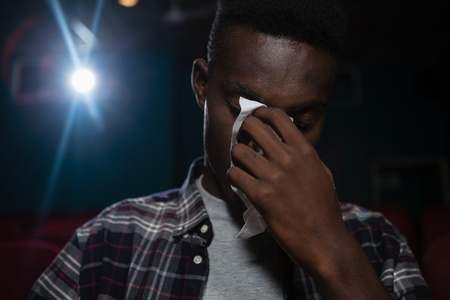 Man getting emotional while watching movie in theatreの写真素材