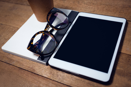 High angle view of digital tablet with diary and eyeglasses on tableの写真素材