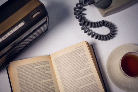 Overhead view of book with tea and telephone by radio on tableの写真素材