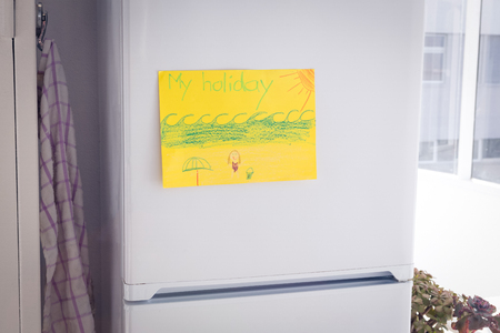 Drawing on yellow paper stuck to refrigerator by window at homeの写真素材