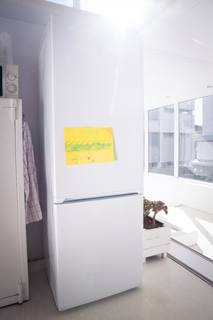 Drawing on yellow paper stuck to refrigerator by glass window at homeの写真素材