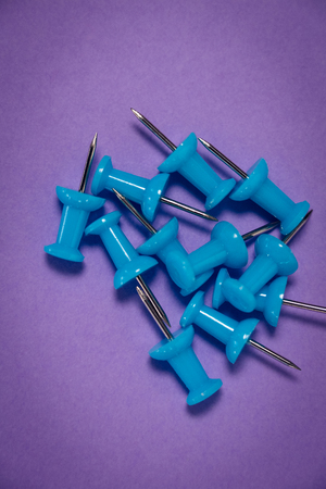 Overhead view of blue paper pins on purple paper