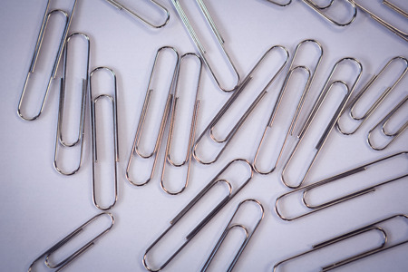 Directly above shot of metallic paper clips on white paperの写真素材