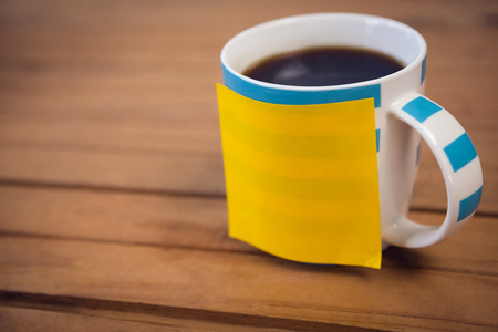 High angle view of adhesive note on coffee cup at wooden tableの写真素材