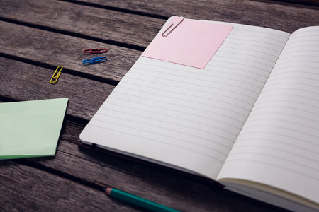 Close-up of diary, sticky notes, pencil and paper clip on wooden tableの写真素材