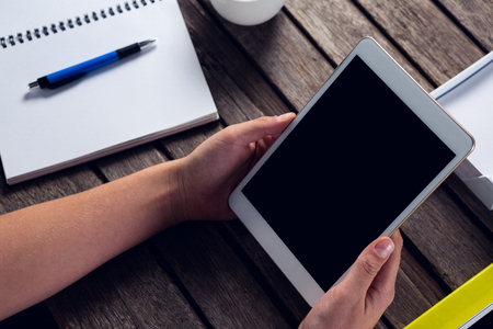 Executive holding digital tablet at desk in officeの写真素材