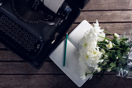 Overhead of vintage typewriter, diary and flowers on wooden tableの写真素材