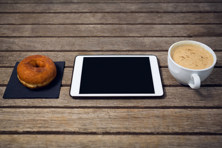 HIgh angle view of digital tablet with coffee cup donut on wooden tableの写真素材