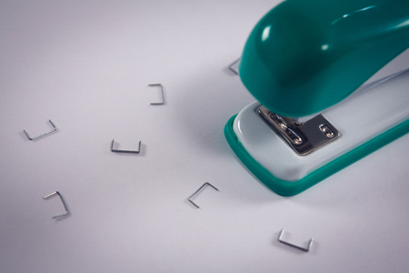 Close-up of stapler and pins on white backgroundの写真素材