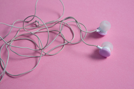 Close-up of pink earphones on pink background
