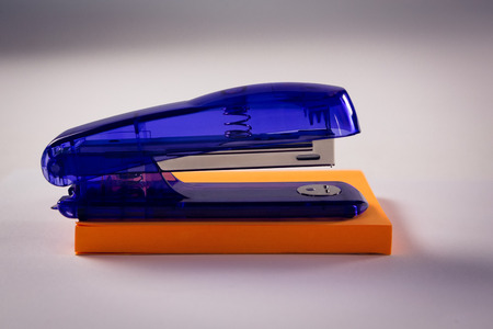 Close-up of stapler on sticky note on white backgroundの写真素材