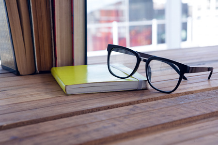 Close-up of spectacles on open book at deskの写真素材