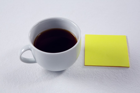 Close-up of black coffee with blank sticky note on white backgroundの写真素材