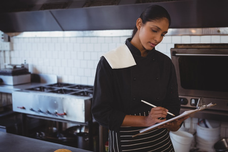 Young waitress with clipboard standing in cafeの写真素材