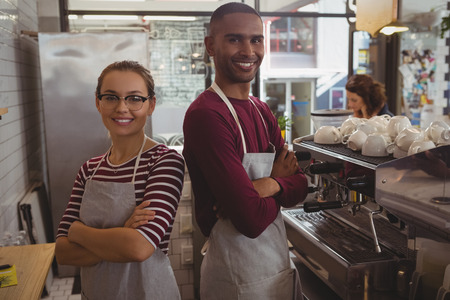 Portrait of smiling confident young owners standing in cafeの写真素材