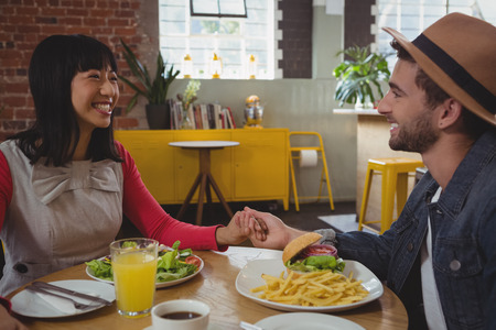 Happy young couple holding hands at cafeの写真素材