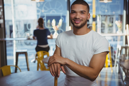 Portrait of smiling waiter with female customer in background at cafeの写真素材