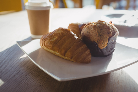 Croissants and muffin in plate on table at cafe during sunny dayの写真素材