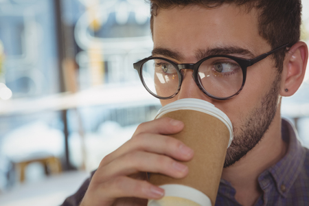 Close-up of man looking away while drinking coffeeの写真素材