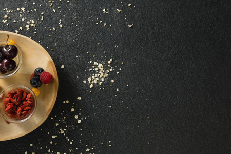 Fruits and dried fruits in wooden plate on black backgroundの写真素材