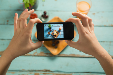 Close-up of hands taking photo of breakfast with mobile phoneの写真素材