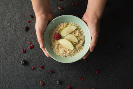 Close-up of hands holding a bowl of fruit cerealの写真素材