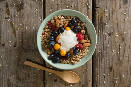 Bowl of breakfast cereals with spoon on wooden table