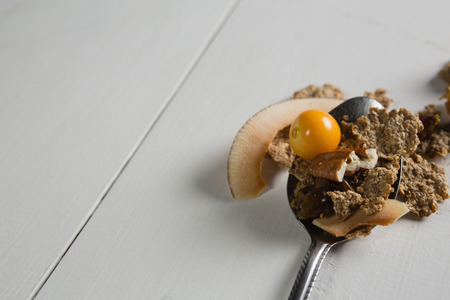 Close-up of wheat flakes and fruit in spoonの写真素材