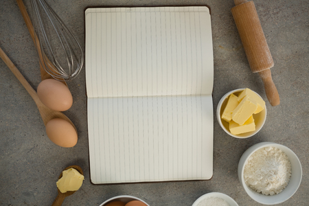 Overhead view of ingredients amidst open cookbook on tableの写真素材