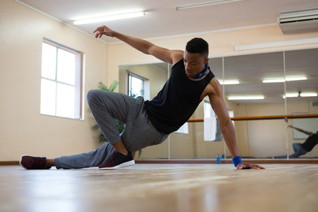 Full length of male dancer practicing on wooden floor at studioの写真素材