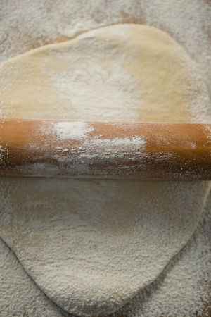 Overhead view of wooden rolling pin on rolled doughの写真素材