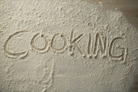 High angle view of cooking text on flour at wooden tableの写真素材