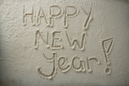 Overhead view of happy new year text on flour at wooden table