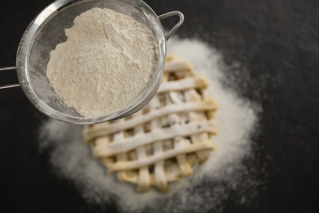 Close up of strainer over pie on tableの写真素材