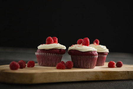 Cupcakes on wooden cutting board against black backgroundの写真素材