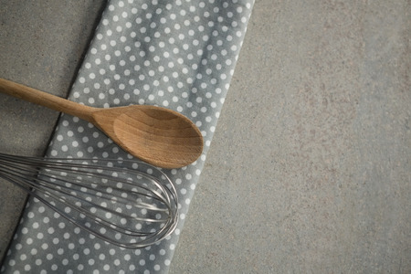 High anlge view of wooden spoon with wire whisk on napkin at tableの写真素材