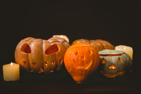 Illuminated jack o lanterns with candles over black backgroundの写真素材