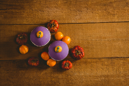Overhead view of cup cakes with small pumpkins on wooden tableの写真素材