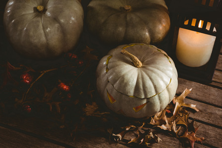 High angle view of white jack o lanterns with autumn leaves by candle on tableの写真素材