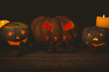 Illuminated jack o lantern with candles arranged on table during Halloweenの写真素材