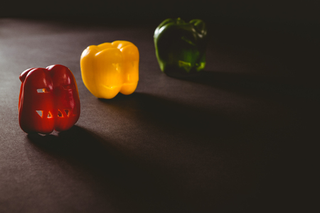 Colorful carved bell peppers on table during Halloweenの写真素材