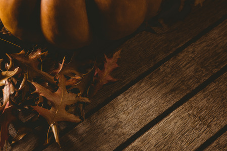 Cropped image of pumpkin with autumn leaves on wooden tableの写真素材