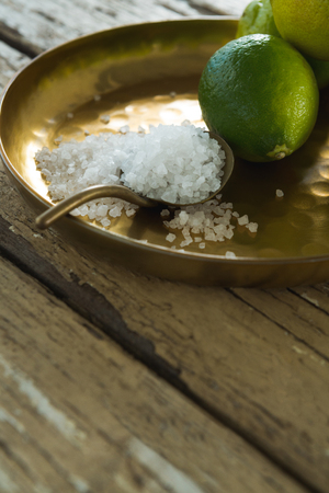 Close-up of lemon and salt in plate on wooden tableの写真素材