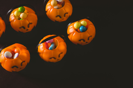 High angle view of jack o lantern containers with sweet food over black backgroundの写真素材