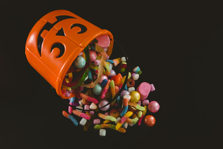 High angle view of bucket with various sweet food over black background