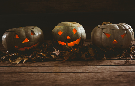 White jack o lanterns with autumn leaves arranged on tableの写真素材