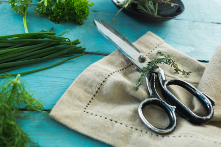 Close-up of various herbs, scissors and napkin on wooden tableの写真素材